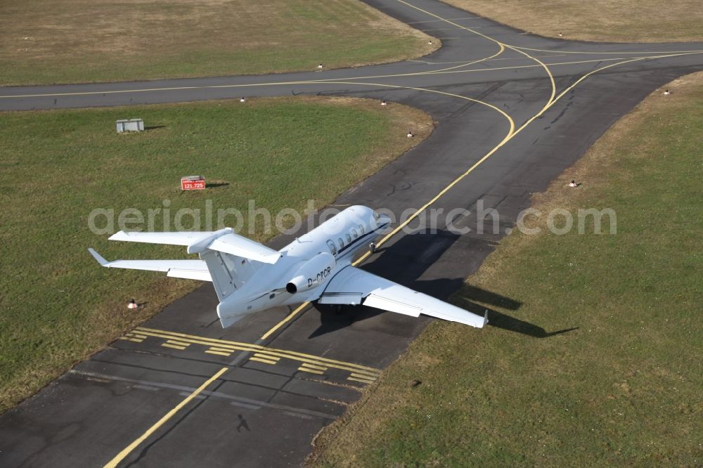 Egelsbach from the bird's eye view: Private jet aircraft EMB-505 Phenom 300 with the registration D-CRCR on the taxiway of Egelsbach Airport in Hesse