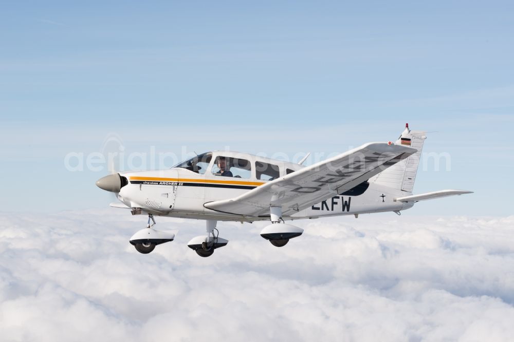 Gnarrenburg from the bird's eye view: Piper Pa28 Archer II D-EKFW Aircraft in flight above the clouds near Gnarrenburg in the state Lower Saxony, Germany. The Piper PA-28 Cherokee is a single-engine, four-seater light aircraft from the US aircraft manufacturer Piper Aircraft Corporation