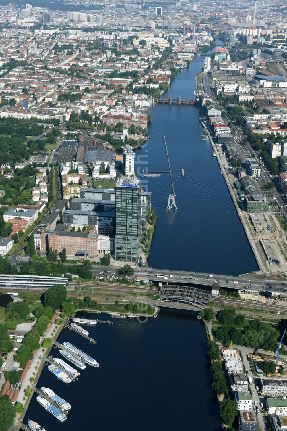 Aerial photograph Berlin - River - bridge structure Else bridge over the Spree in Berlin. Eyecatcher is the sculpture Molecule Man by Jonathan Borofsky whose three figures symbolizes the coming together of the three districts Treptow, Kreuzberg and Friedrichshain