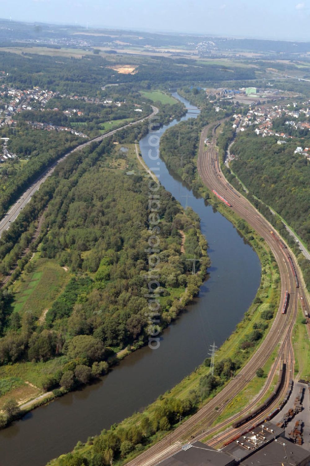 Bous from above - Blick aus Osten entlang der Saar bei Bous im Saarland. Am linken Saarufer erstreckt sich die Autobahn 620 vorbei an Wadgassen. Am rechten Ufer erstrecken sich Gleise. View from east along the Saar river.