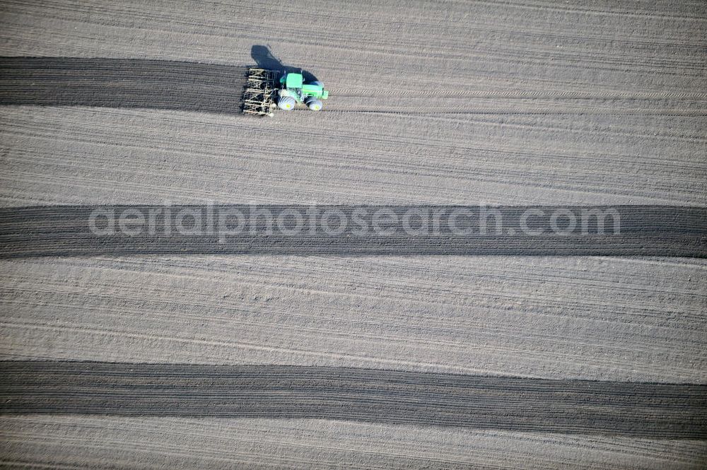 Großbrembach from above - A tractor pulls a plow with his tracks on a field near Großbrembach