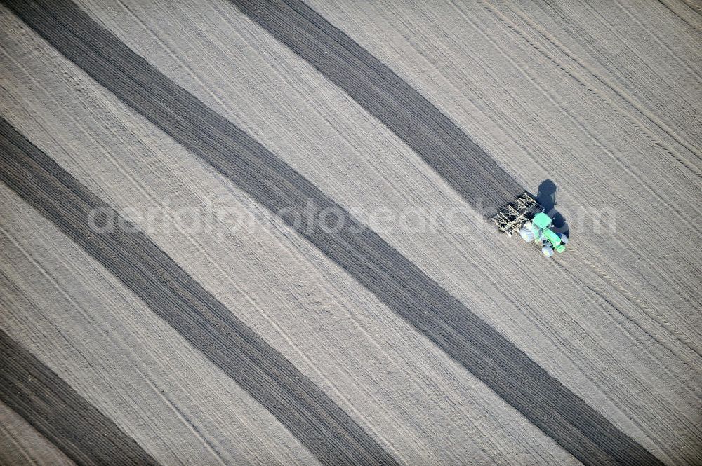 Großbrembach from the bird's eye view: A tractor pulls a plow with his tracks on a field near Großbrembach