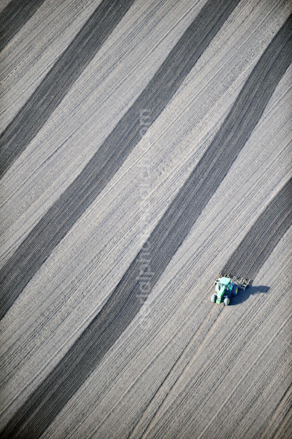 Großbrembach from above - A tractor pulls a plow with his tracks on a field near Großbrembach