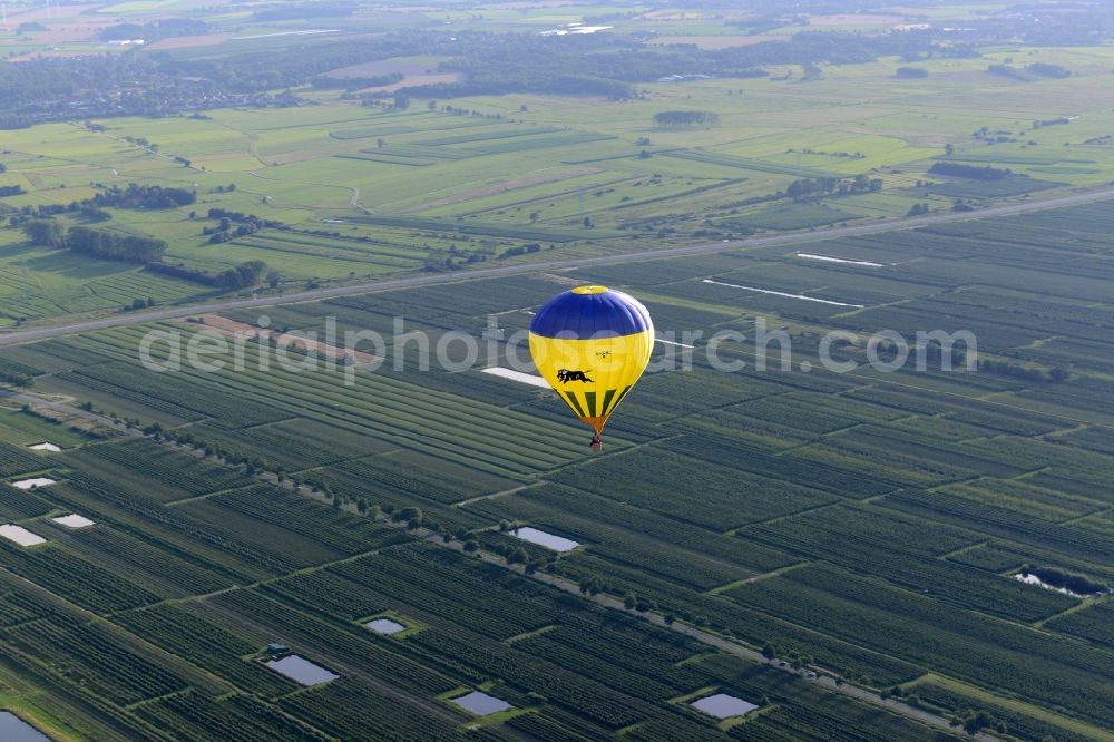 Aerial photograph Jork - A yellow- blue coloured hot-air balloon with the identifier D-ORMC in flight above Jork in the state Lower Saxony