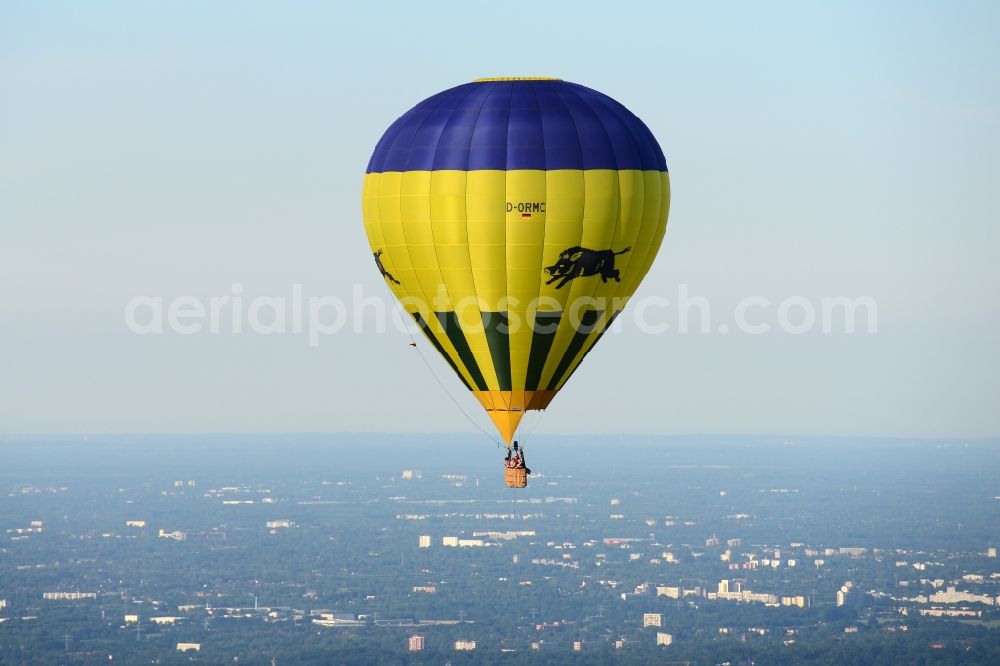 Jork from the bird's eye view: A yellow- blue coloured hot-air balloon with the identifier D-ORMC in flight above Jork in the state Lower Saxony