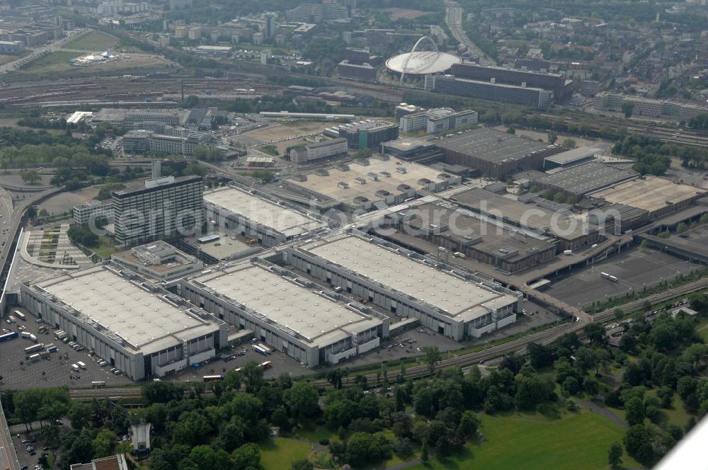 KÖLN from above - Blick auf das Gelände der Kölnmesse östlich des Rheins. Sie ist ein wichtiger Faktor für den Wirtschaft Kölns und den Wirtschaftsstandort Köln. Die Koelnmesse organisiert regelmäßig über 70 Messen im In- und Ausland. 25 davon gelten als die bedeutendsten Messen im jeweiligen Wirtschaftszweig. Somit ist die Koelnmesse größter Veranstalter von Messen auf einem eigenen Gelände und, gemessen an ihrer Ausstellungsfläche, die viert größte Messe weltweit. Jährlich werden rund 2,3 Millionen Besucher aus fast 200 Ländern gezählt. Das Gelände bietet Kapazitäten für Tagungen mit über 19.500 Teilnehmern und den Rahmen für Kongresse mit begleitenden Ausstellungen.