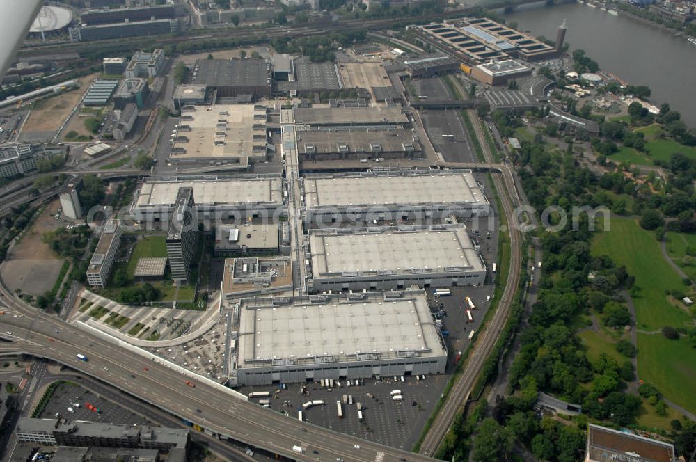 KÖLN from above - Blick auf das Gelände der Kölnmesse östlich des Rheins. Sie ist ein wichtiger Faktor für den Wirtschaft Kölns und den Wirtschaftsstandort Köln. Die Koelnmesse organisiert regelmäßig über 70 Messen im In- und Ausland. 25 davon gelten als die bedeutendsten Messen im jeweiligen Wirtschaftszweig. Somit ist die Koelnmesse größter Veranstalter von Messen auf einem eigenen Gelände und, gemessen an ihrer Ausstellungsfläche, die viert größte Messe weltweit. Jährlich werden rund 2,3 Millionen Besucher aus fast 200 Ländern gezählt. Das Gelände bietet Kapazitäten für Tagungen mit über 19.500 Teilnehmern und den Rahmen für Kongresse mit begleitenden Ausstellungen.