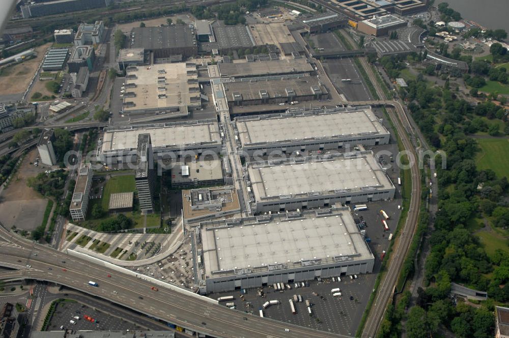 KÖLN from the bird's eye view: Blick auf das Gelände der Kölnmesse östlich des Rheins. Sie ist ein wichtiger Faktor für den Wirtschaft Kölns und den Wirtschaftsstandort Köln. Die Koelnmesse organisiert regelmäßig über 70 Messen im In- und Ausland. 25 davon gelten als die bedeutendsten Messen im jeweiligen Wirtschaftszweig. Somit ist die Koelnmesse größter Veranstalter von Messen auf einem eigenen Gelände und, gemessen an ihrer Ausstellungsfläche, die viert größte Messe weltweit. Jährlich werden rund 2,3 Millionen Besucher aus fast 200 Ländern gezählt. Das Gelände bietet Kapazitäten für Tagungen mit über 19.500 Teilnehmern und den Rahmen für Kongresse mit begleitenden Ausstellungen.