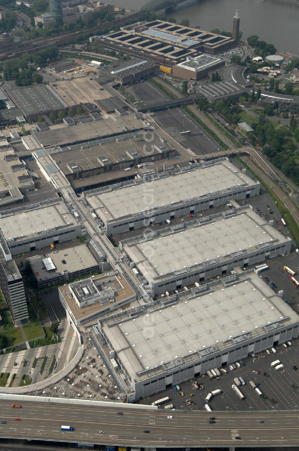 Aerial photograph KÖLN - Blick auf das Gelände der Kölnmesse östlich des Rheins. Sie ist ein wichtiger Faktor für den Wirtschaft Kölns und den Wirtschaftsstandort Köln. Die Koelnmesse organisiert regelmäßig über 70 Messen im In- und Ausland. 25 davon gelten als die bedeutendsten Messen im jeweiligen Wirtschaftszweig. Somit ist die Koelnmesse größter Veranstalter von Messen auf einem eigenen Gelände und, gemessen an ihrer Ausstellungsfläche, die viert größte Messe weltweit. Jährlich werden rund 2,3 Millionen Besucher aus fast 200 Ländern gezählt. Das Gelände bietet Kapazitäten für Tagungen mit über 19.500 Teilnehmern und den Rahmen für Kongresse mit begleitenden Ausstellungen.