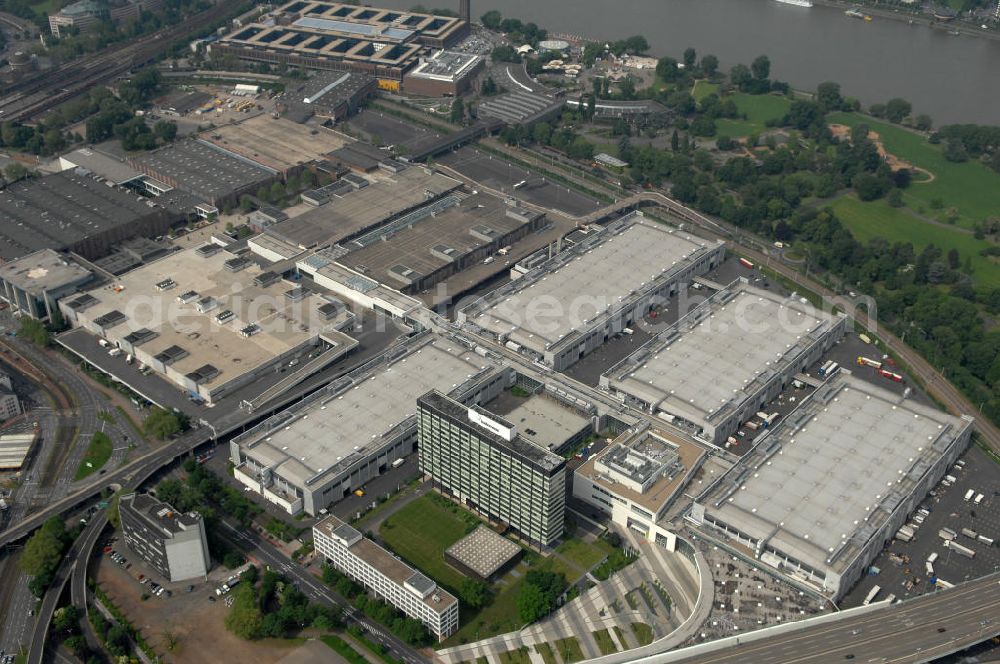 KÖLN from the bird's eye view: Blick auf das Gelände der Kölnmesse östlich des Rheins. Sie ist ein wichtiger Faktor für den Wirtschaft Kölns und den Wirtschaftsstandort Köln. Die Koelnmesse organisiert regelmäßig über 70 Messen im In- und Ausland. 25 davon gelten als die bedeutendsten Messen im jeweiligen Wirtschaftszweig. Somit ist die Koelnmesse größter Veranstalter von Messen auf einem eigenen Gelände und, gemessen an ihrer Ausstellungsfläche, die viert größte Messe weltweit. Jährlich werden rund 2,3 Millionen Besucher aus fast 200 Ländern gezählt. Das Gelände bietet Kapazitäten für Tagungen mit über 19.500 Teilnehmern und den Rahmen für Kongresse mit begleitenden Ausstellungen.