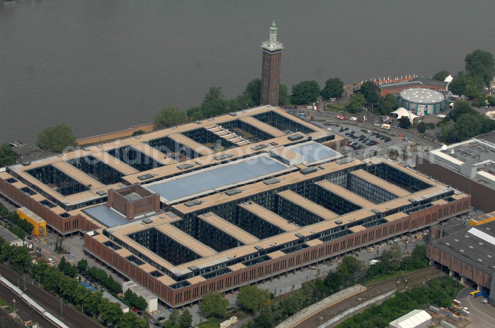 KÖLN from the bird's eye view: Blick auf das Gelände der Kölnmesse östlich des Rheins. Sie ist ein wichtiger Faktor für den Wirtschaft Kölns und den Wirtschaftsstandort Köln. Die Koelnmesse organisiert regelmäßig über 70 Messen im In- und Ausland. 25 davon gelten als die bedeutendsten Messen im jeweiligen Wirtschaftszweig. Somit ist die Koelnmesse größter Veranstalter von Messen auf einem eigenen Gelände und, gemessen an ihrer Ausstellungsfläche, die viert größte Messe weltweit. Jährlich werden rund 2,3 Millionen Besucher aus fast 200 Ländern gezählt. Das Gelände bietet Kapazitäten für Tagungen mit über 19.500 Teilnehmern und den Rahmen für Kongresse mit begleitenden Ausstellungen.