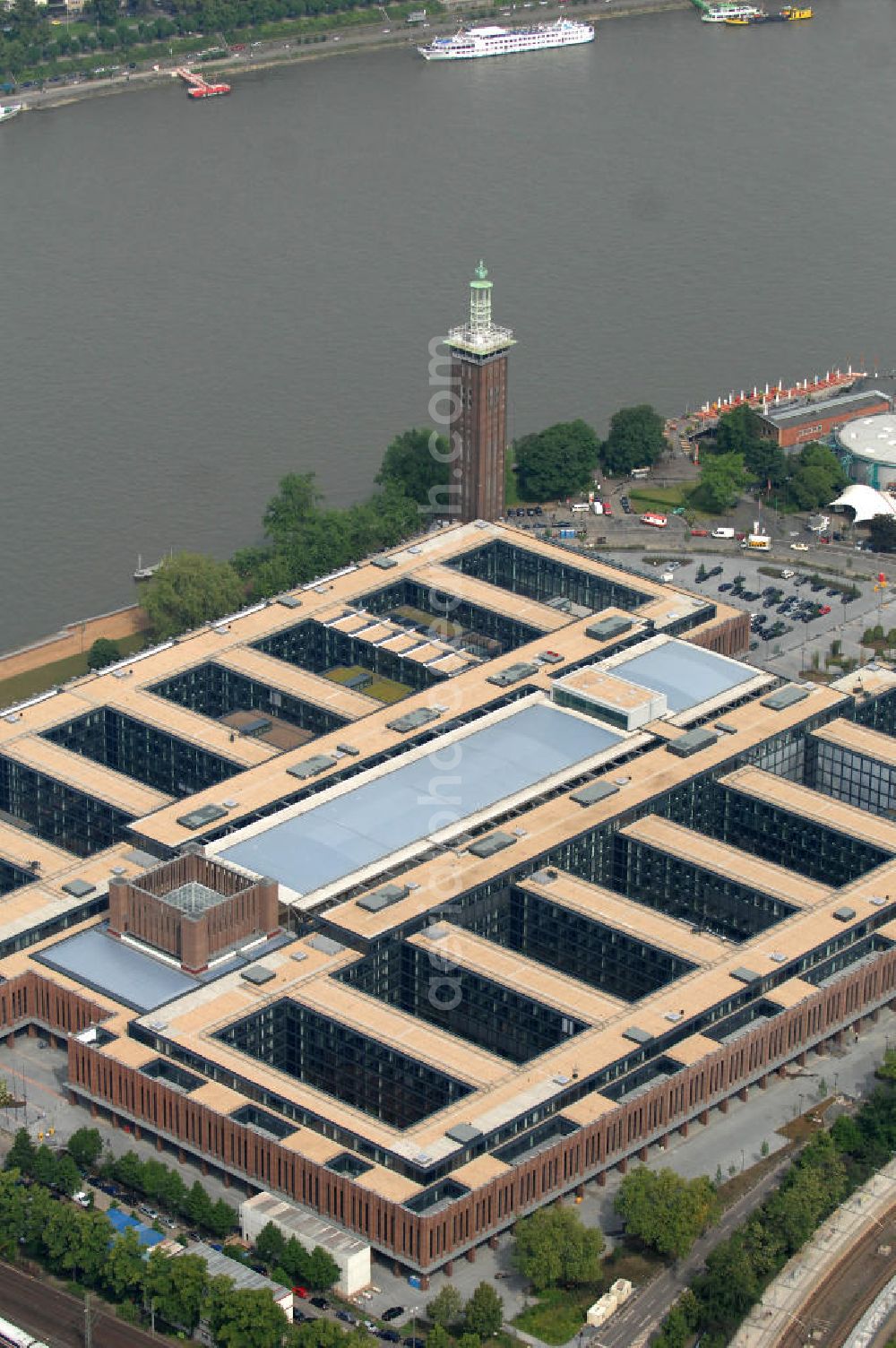 KÖLN from above - Blick auf das Gelände der Kölnmesse östlich des Rheins. Sie ist ein wichtiger Faktor für den Wirtschaft Kölns und den Wirtschaftsstandort Köln. Die Koelnmesse organisiert regelmäßig über 70 Messen im In- und Ausland. 25 davon gelten als die bedeutendsten Messen im jeweiligen Wirtschaftszweig. Somit ist die Koelnmesse größter Veranstalter von Messen auf einem eigenen Gelände und, gemessen an ihrer Ausstellungsfläche, die viert größte Messe weltweit. Jährlich werden rund 2,3 Millionen Besucher aus fast 200 Ländern gezählt. Das Gelände bietet Kapazitäten für Tagungen mit über 19.500 Teilnehmern und den Rahmen für Kongresse mit begleitenden Ausstellungen.