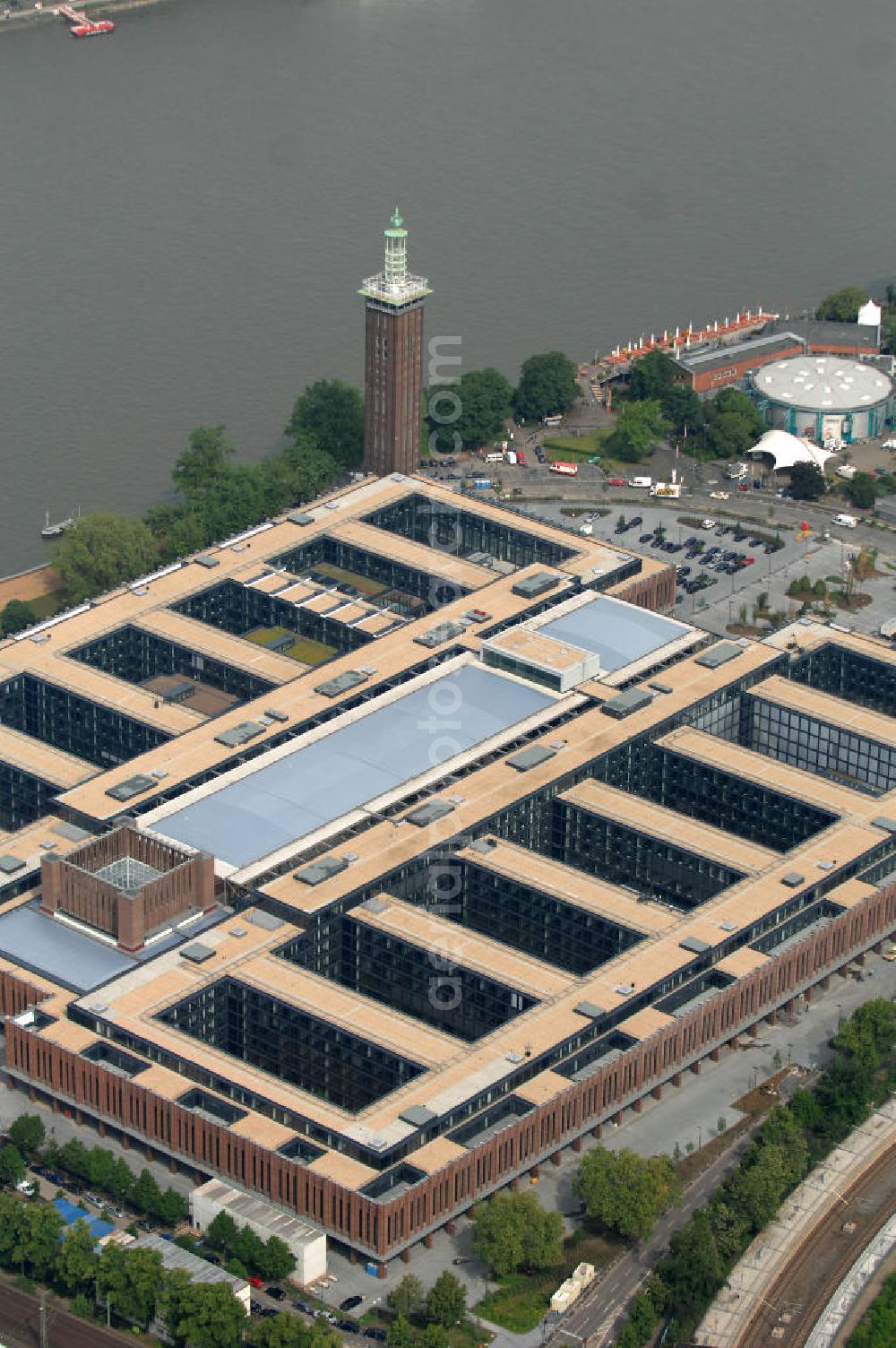 KÖLN from the bird's eye view: Blick auf das Gelände der Kölnmesse östlich des Rheins. Sie ist ein wichtiger Faktor für den Wirtschaft Kölns und den Wirtschaftsstandort Köln. Die Koelnmesse organisiert regelmäßig über 70 Messen im In- und Ausland. 25 davon gelten als die bedeutendsten Messen im jeweiligen Wirtschaftszweig. Somit ist die Koelnmesse größter Veranstalter von Messen auf einem eigenen Gelände und, gemessen an ihrer Ausstellungsfläche, die viert größte Messe weltweit. Jährlich werden rund 2,3 Millionen Besucher aus fast 200 Ländern gezählt. Das Gelände bietet Kapazitäten für Tagungen mit über 19.500 Teilnehmern und den Rahmen für Kongresse mit begleitenden Ausstellungen.