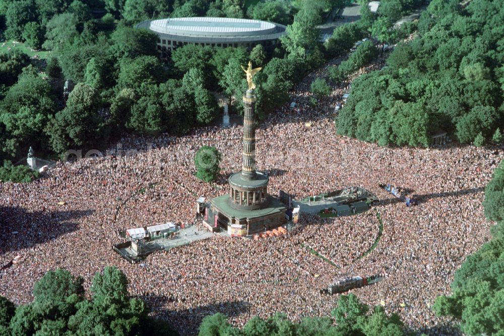 Berlin from the bird's eye view: Participants in the Love Parade music festival on the event concert area on the Great Star at the Victory Column and the Strasse des 17. Juni in the district Tiergarten in Berlin, Germany