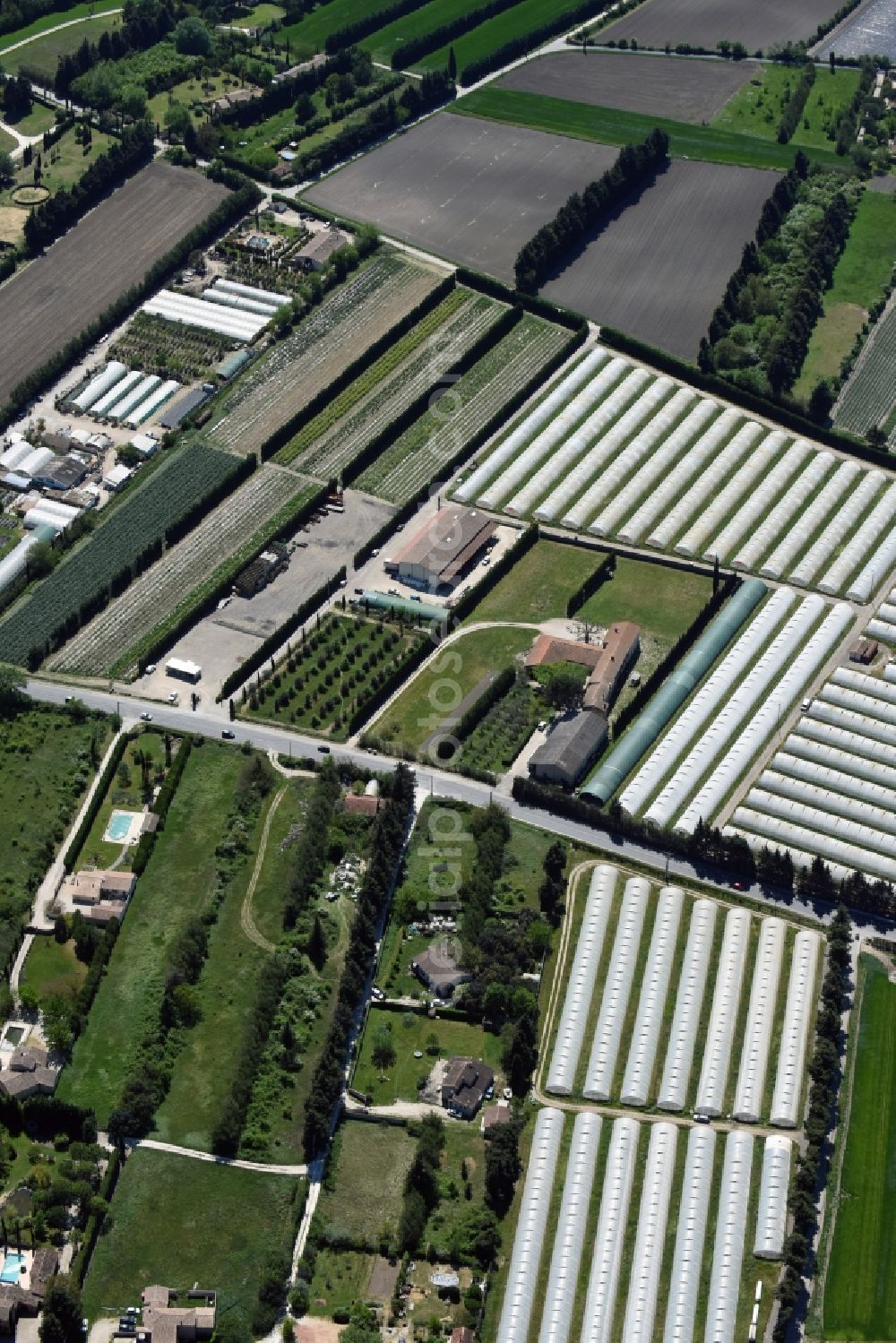 Gordes from the bird's eye view: Glass roof surfaces in the greenhouse for vegetable growing ranks in Gordes in Provence-Alpes-Cote d'Azur, France