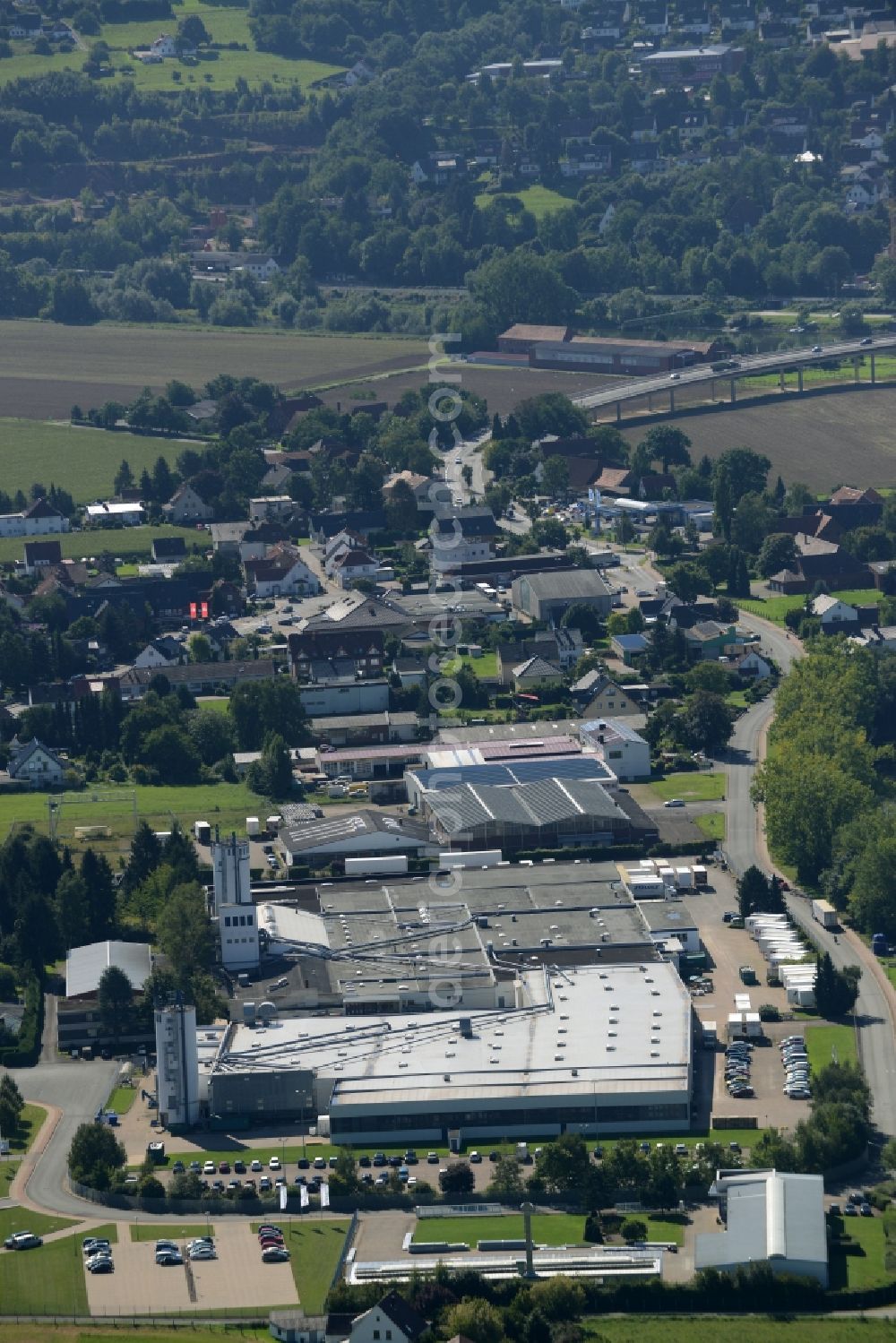 Uffeln from the bird's eye view: Commercial and industrial area in the West of Uffeln on the Eastern riverbank of the river Weser in the state of North Rhine-Westphalia. View from the North over the industrial and commercial area on pond Kiesteich. The commerce park includes several halls, office buildings and outdoor areas