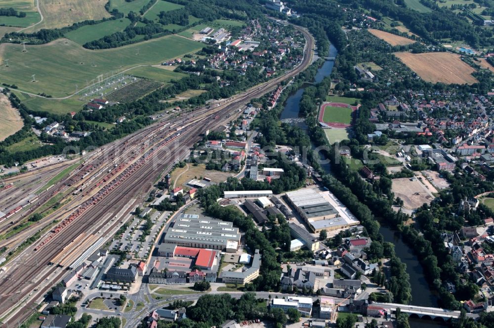 Saalfeld/Saale from above - There is a commercial area with trade and industry and craft enterprises between the Kulmbach Street and Huetten Street in Saalfeld in Thuringia. Beyond the Kulmbach street extend the tracks of the freight station Saalfeld, on which are placed and ranked several freight cars. On the other side of the river Saale is the stadium Saale meadows. About the Saale bridge the historic old town with the ruins to reach High swarm and the city gate Saaletor