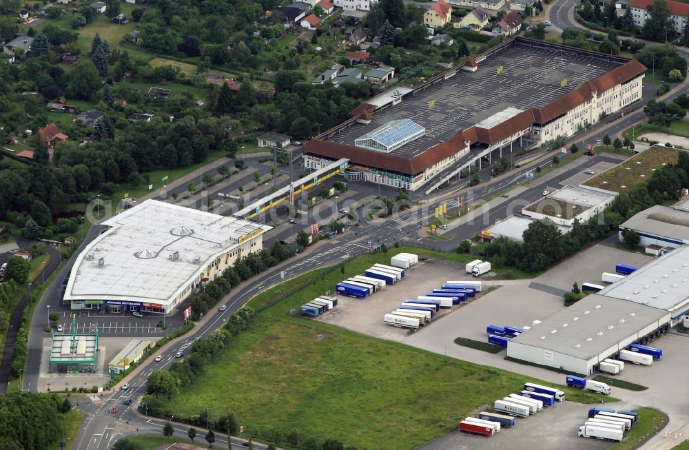 Aerial photograph Eisenach - Unter dem Dach mit Parkplätzen betreibt die Supermarkt-Kette Marktkauf in der Mühlhäuser-Straße in Eisenach im Bundesland Thüringen eine Filiale. In dem Einkaufszentrum befinden sich weitere Geschäfte wie ein Baumarkt-Discounter, ein Erotik-MArkt, ein Möbelhaus und der Elektronikfachmarkt MEDIMAX. Am rechten Bildrand sind die Lagerhalen des Logistik-anbieters Raben zu sehen. //Under the roof with parking the supermarket chain operates in the MARKTKAUF Muhlhauser Road in Eisenach in Thuringia a branch. In the shopping center there are other shops such as a hardware store discounters, an adult market, a furniture store and the consumer electronics market MEDIMAX. At one end of the bearing Halen of the logistics provider can be seen RABEN