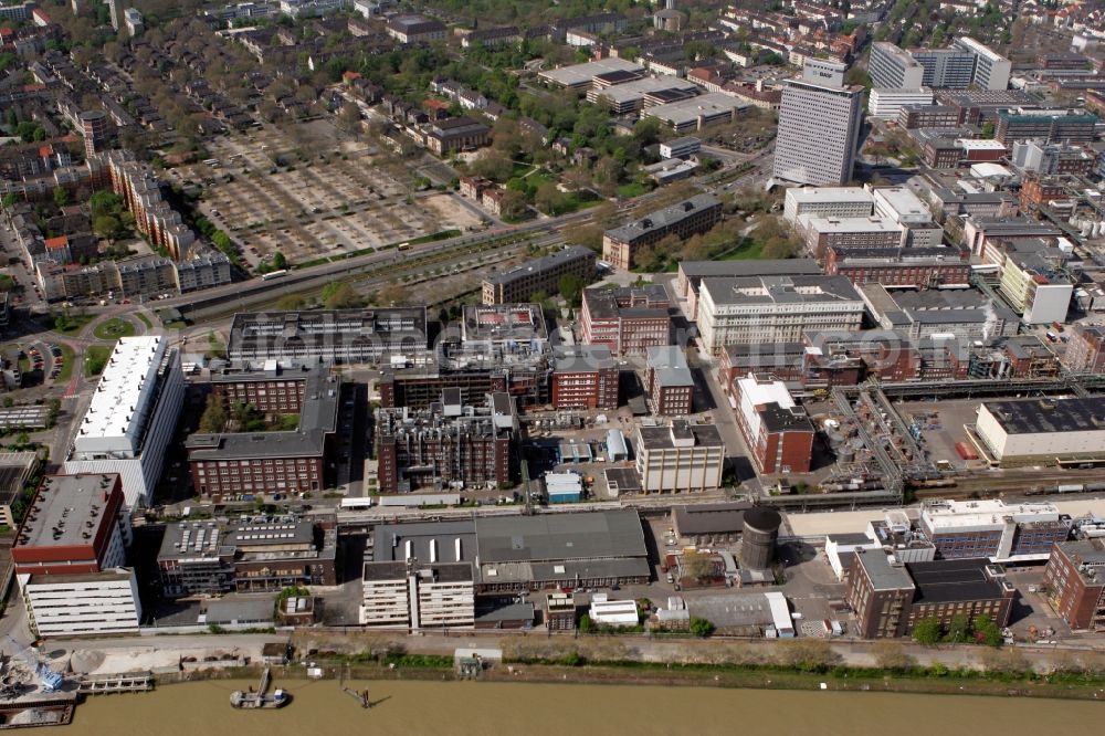 Aerial photograph Ludwigshafen am Rhein - Commerce district on the Rhine in Ludwigshafen in the state of Rhineland-Palatinate. The area is located in the North of the town and includes commercial and business buildings, factories and halls. The area is located on the riverbank of the Rhine which forms the border to Baden-Wuerttemberg. The tower in the background is the high rise and headquarters of BASF SE, an international chemical producer