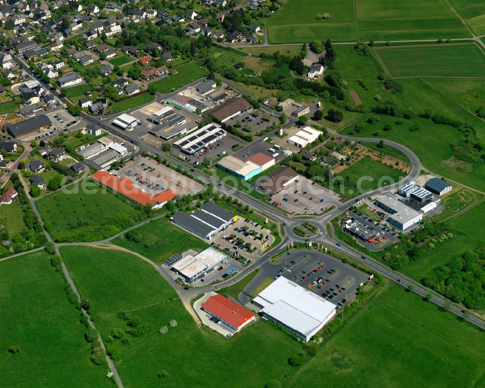 Rennerod from above - Commercial area in the South of Rennerod in the state of Rhineland-Palatinate. The town is located in the Westerwald region and county district on federal highway B54 - where the commercial area with stores, parking lots and shopping facilities is located. It is surrounded by industrial areas, agricultural fields and meadows