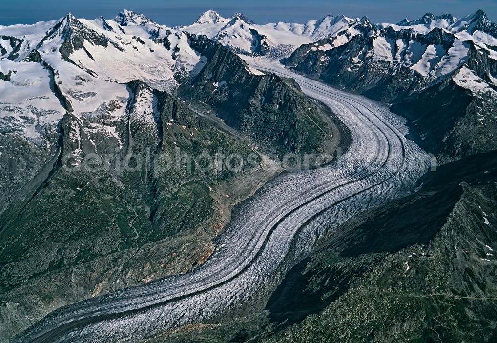 Aerial image Fieschertal - Glaciers Grosser Aletschgletscher in the rock and mountain landscape in Fieschertal in Wallis, Switzerland. The ice tongue of the Great Aletsch Glacier, whose rippled surface includes several streams of moraine material, is around 23 Kilometers long. Great Aletsch Glacier is the largest glacier in the Alps
