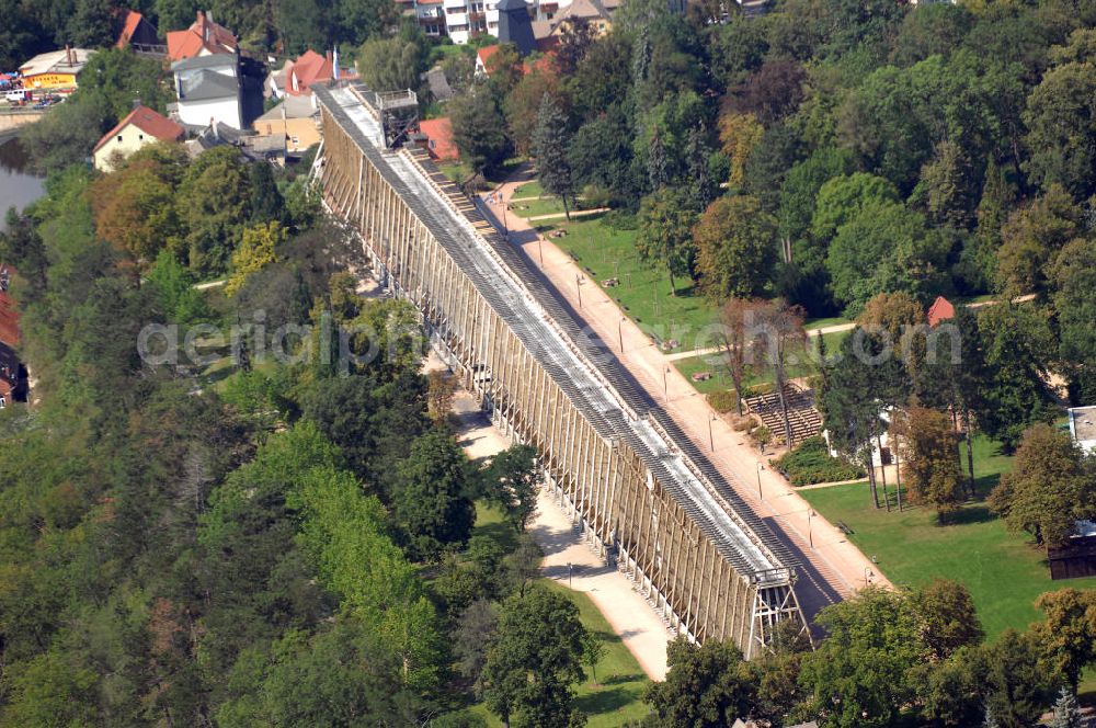 Aerial image Bad Kösen - Ein Gradierwerk ist eine Anlage zur Salzgewinnung. Sie besteht aus einem Holzgerüst, das mit Reisigbündeln verfüllt ist. Gradierwerke werden in Deutschland oft zu Kurzwecken betrieben. Durch die herabrieselnde Sole wird die Luft in der Nähe des Gradierwerks mit Salz angereichert, die Wassertröpfchen binden Partikel in der Luft. Dies wirkt sich ähnlich wie bei Seeluft beispielsweise bei Pollenallergikern und Asthmatikern und an deren positiv aus. Bad Kösen 2007/08/07 A graduation tower consists of a wooden wall-like frame which is stuffed with bundles of brushwood. It increases the concentration of a solution of mineral salts. The salty water runs down the tower, and — through the action of breeze and sun — partly evaporates; at the same time certain mineral content of the solution are left behind on the sticks of brushwood.