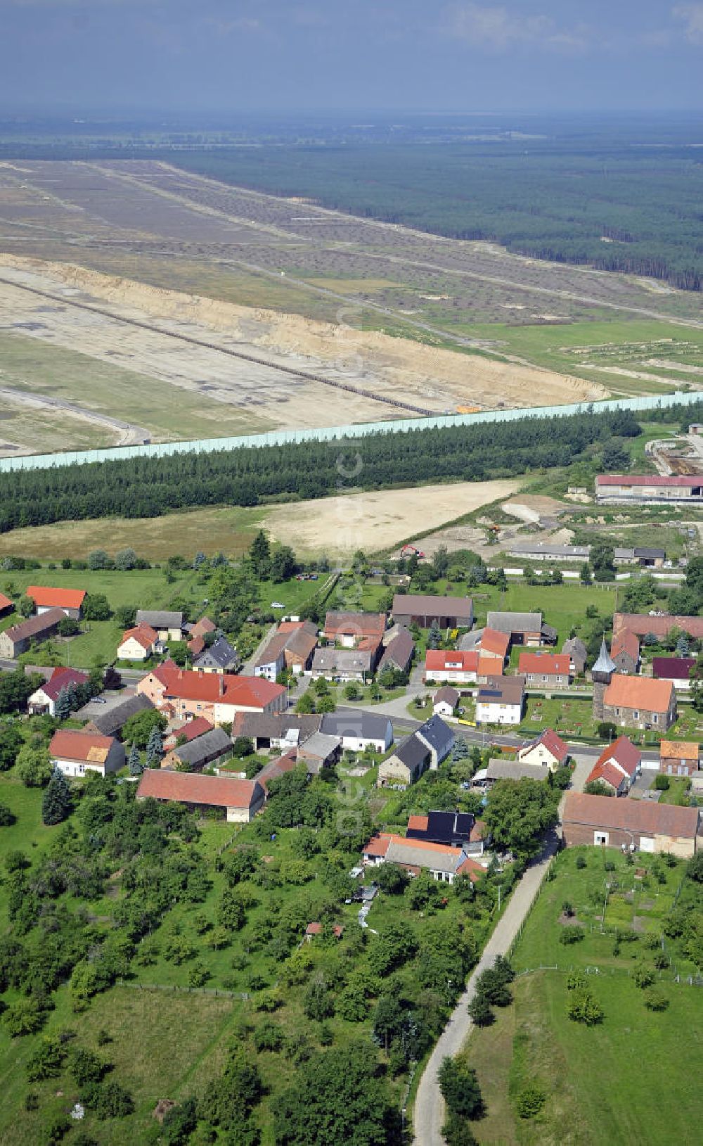 Aerial image Grießen - Blick auf das Dorf Grießen am Braunkohle-Tagebau Jänschwalde. Der Abbau des 8 bis 12 Meter mächtigen Kohleflözes erfolgt durch die Vattenfall Europe Mining AG. Zwischen Tagebau und Dorf wurde ein Grünschutzgürtel angelegt. View of the village Grießen at the lignite-mining Janschwalde. The mining of the 8-12 meters thick coal bed is made by the Vattenfall Europe Mining AG. Between the mine and a the village a green protection belt has been created.