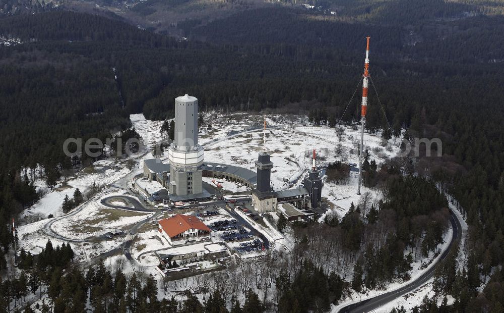 Schmitten from the bird's eye view: Blick auf den winterlich mit Schnee bedeckte Großen Feldberg, der mit 881,5 m der höchste Berg des Mittelgebirges Taunus und des Rheinischen Schiefergebirges ist. Auf dem Gipfel befinden sich ein Fernmeldeturm, ein Rohrmast des Hessischen Rundfunks, der Aussichtsturm und die Gaststätte Feldberghof.