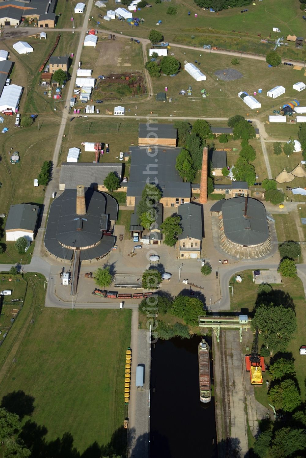 Zehdenick from above - Main buildings and technical facilities in the Mildenberg brick work park in the town area of Zehdenick in the state of Brandenburg. The park is an industrial memorial, surrounded by lakes and ponds. The compound consists of the company sites of two former brick works and is located in the North of the Mildenberg part of the town. View of the works, chimneys and factories of the compound