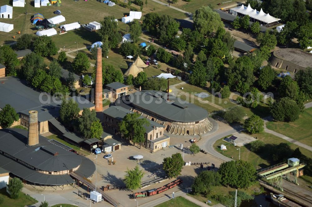 Zehdenick from above - Main buildings and technical facilities in the Mildenberg brick work park in the town area of Zehdenick in the state of Brandenburg. The park is an industrial memorial, surrounded by lakes and ponds. The compound consists of the company sites of two former brick works and is located in the North of the Mildenberg part of the town. View of the works, chimneys and factories of the compound