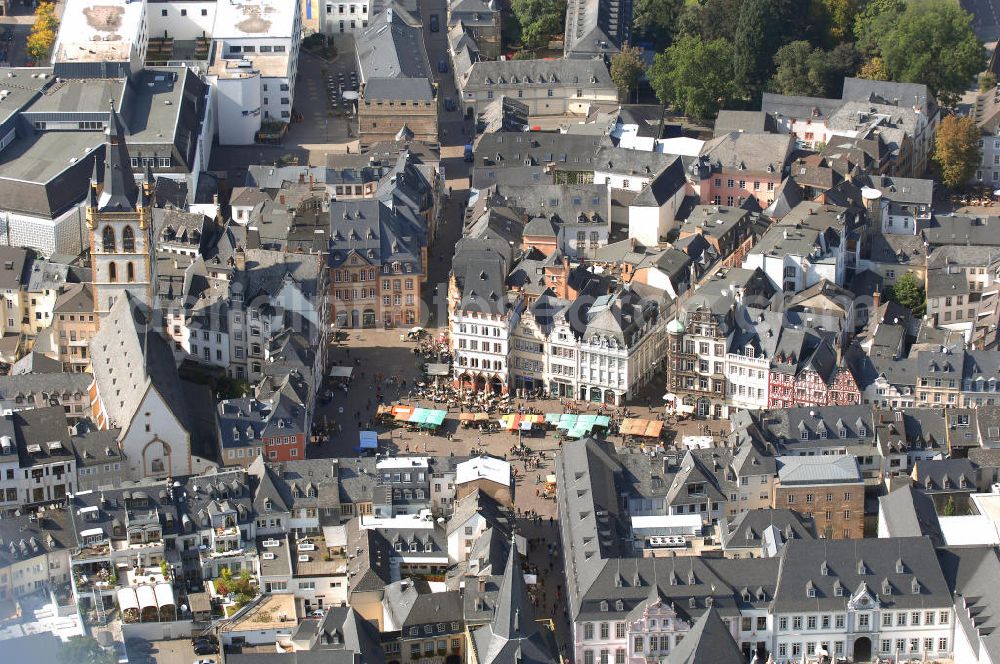 Aerial photograph TRIER - Der Hauptmarkt von Trier ist der zentrale und einer der größten Plätze der Stadt.Er befindet sich im historischen Stadtkern unmittelbar vor der historischen Domstadt im heutigen Bezirk Mitte/Gartenfeld. Die wichtigsten städtischen Geschäftsstraßen treffen hier zusammen. Im Jahr 958 wurde der Hauptmarkt durch Erzbischof Heinrich I. mit dem Marktkreuz als Hoheitssymbol ausgestattet. Der Hauptmarkt diente der mittelalterlichen Stadt als Warenverkaufs- und Handelsplatz.Die historische Marktumbauung mit Häusern der Renaissance, des Barock, des Klassizismus und des Späthistorismus ist zu zwei Dritteln bewahrt. Prägend sind heute zahlreiche volumige und städtisch-repräsentative Gebäude, darunter etwa die Hauptwache oder das ehemalige Domhotel im Neorenaissance-Stil deutscher Prägung. Noch heute stehen dort außerdem die Steipe, ein um 1430 errichtetes Bürgerhaus und heute das Repräsentationshaus des Stadtrats sowie das Rote Haus mit dem Spruch über die sagenhafte Gründung Triers durch Trebeta. Die Kirche St. Gangolf ist nur über ein Barocktor vom Markt aus zugänglich und ansonsten komplett umbaut.