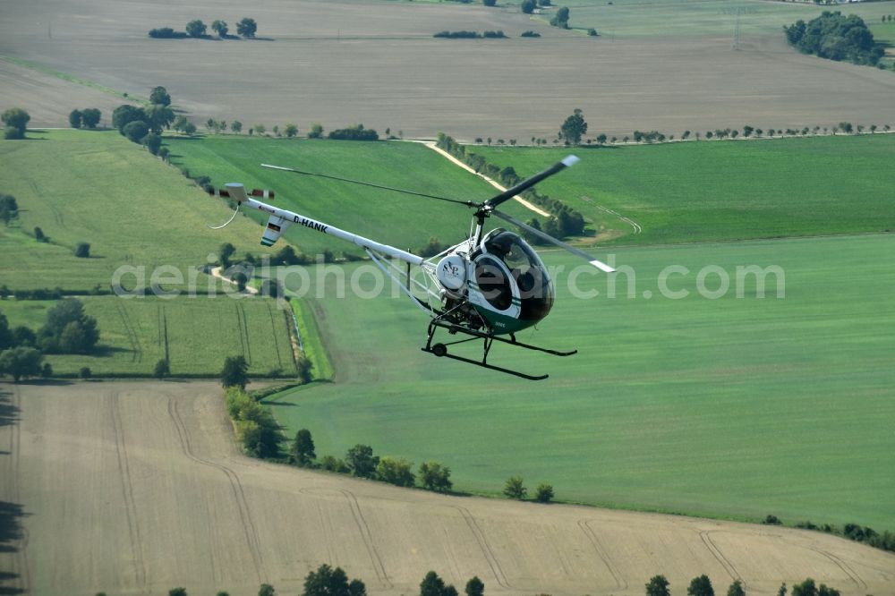 Riesigk from the bird's eye view: Helicopter in flight Hughes 300 - Schweizer 300C call sign D-HANK over the air space in Riesigk in the state Saxony-Anhalt