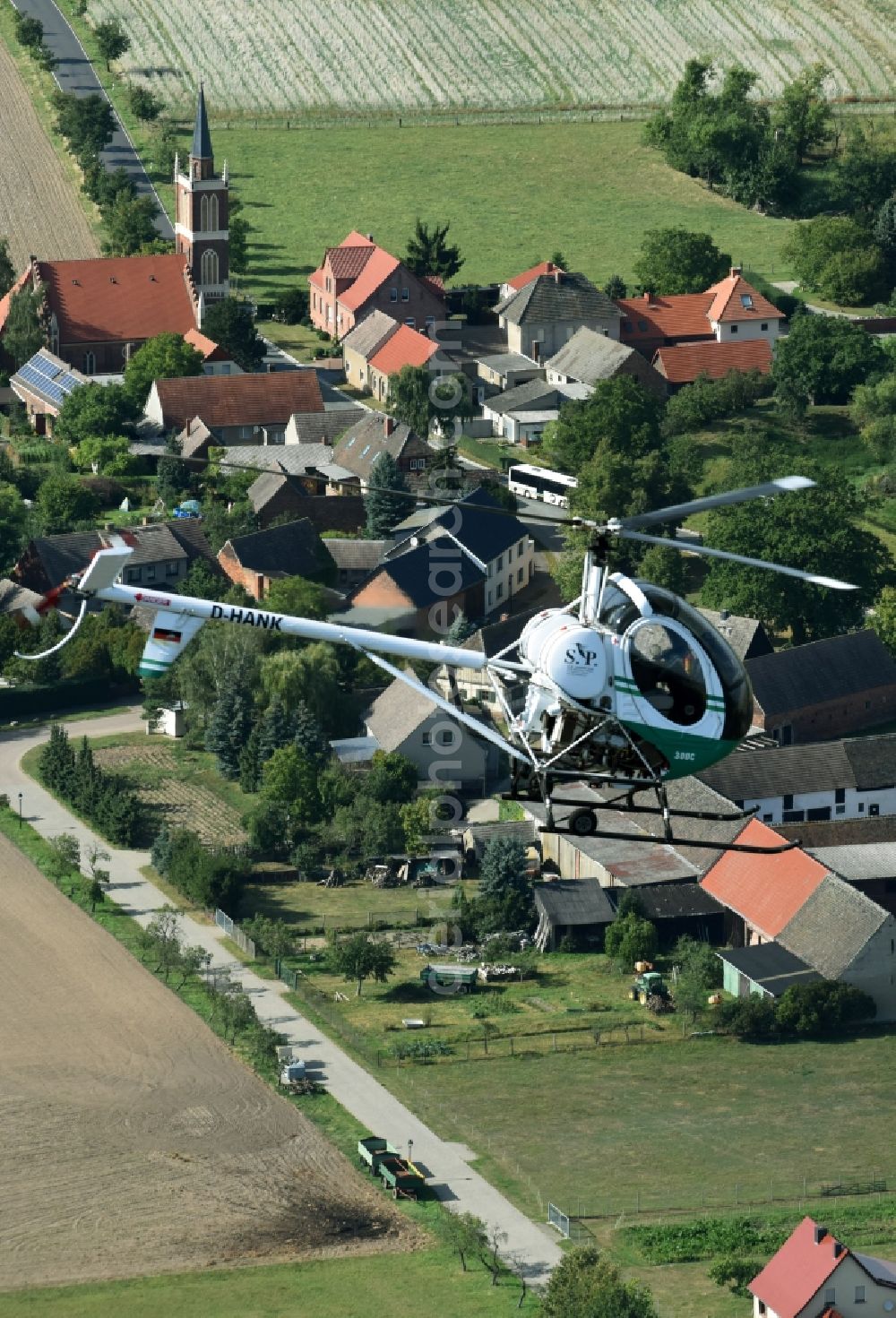 Aerial photograph Riesigk - Helicopter in flight Hughes 300 - Schweizer 300C call sign D-HANK over the air space in Riesigk in the state Saxony-Anhalt