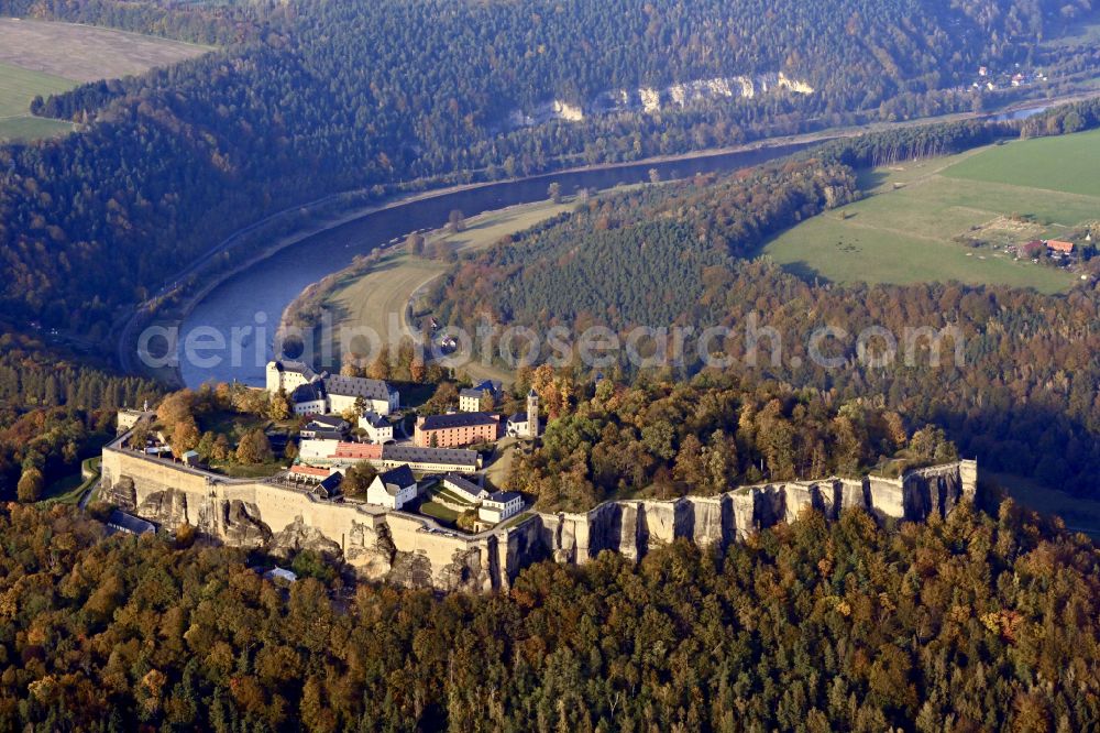 Königstein from above - Autumnal discolored vegetation view the Fortress Koenigstein at the river Elbe in the county district of Saxon Switzerland East Erzgebirge in the state of Saxony. The fortress is one of the largest mountain fortresses in Europe and is located amidst the Elbe sand stone mountains on the flat top mountain of the same name