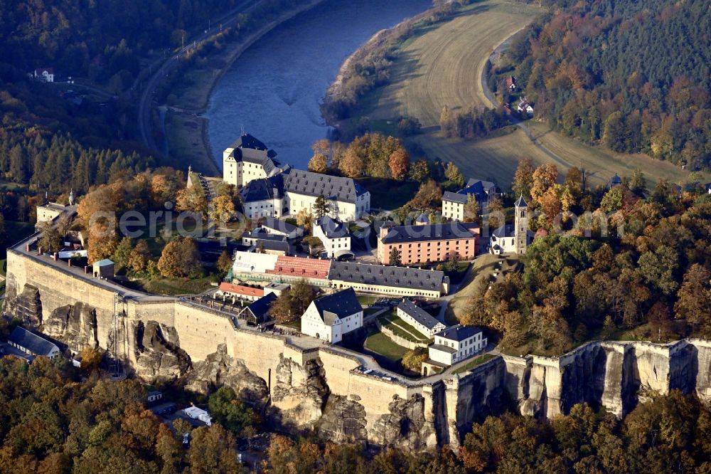 Königstein from the bird's eye view: Autumnal discolored vegetation view the Fortress Koenigstein at the river Elbe in the county district of Saxon Switzerland East Erzgebirge in the state of Saxony. The fortress is one of the largest mountain fortresses in Europe and is located amidst the Elbe sand stone mountains on the flat top mountain of the same name