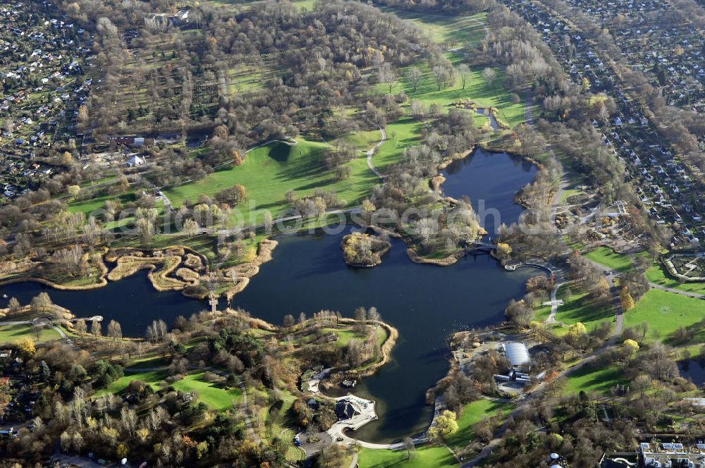 Berlin from above - Herbststimmung im Britzer Garten,benannt nach dem Berliner Ortsteil Britz, wurde für die Bundesgartenschau 1985 angelegt, um der damals vom Umland abgeschnittenen Bevölkerung im Süden West-Berlins einen neuen Landschaftspark zu bieten.Der Britzer Garten wurde auf Ackerflächen und Kleingartenkolonien angelegt; weitestgehend wurden jedoch vorhandene Kleingartenkolonien erhalten. Er befindet sich am südwestlichen Rand des damaligen Berliner Bezirkes Neukölln und grenzt an den Bezirk Tempelhof mit dem Ortsteil Mariendorf an. Er wird durch die Hauptstraßenachsen Mariendorfer Damm, Mohriner Allee, Buckower Damm und Alt-Buckow / Marienfelder Allee eingerahmt. Am Rand dieser Hauptstraßen befindet sich meist offene Wohnbebauung. Noch im Eröffnungsjahr 1985 bestand die planerische Absicht, eine Verlängerung der Berliner Stadtautobahn von der Anschlussstelle Gradestraße durch das Gartengelände hindurch bis zur Berliner Stadtgrenze zu bauen, um dort einen neuen Grenzübergang mit Weiterführung zum Berliner Ring einrichten zu können.Der Britzer Garten hat 90 Hektar Fläche und bietet Natur und Gartenkunst (Rosengarten, Rhododendronhain), Spiellandschaften und ausgedehnte Liegewiesen, Architektur und Kunst (Karl-Foerster-Pavillon), Seen und Hügel sowie bunte Blumenbeete. Neben dem Restaurant am Kalenderplatz steht außerdem die mit 99 Metern Durchmesser größte Sonnenuhr Europas. Sie wurde von den Architekten Jürgen Dirk Zilling, Jasper Halfmann und Klaus Zillich geplant.