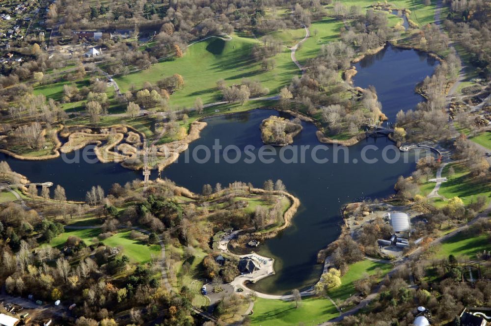 Berlin from the bird's eye view: Herbststimmung im Britzer Garten,benannt nach dem Berliner Ortsteil Britz, wurde für die Bundesgartenschau 1985 angelegt, um der damals vom Umland abgeschnittenen Bevölkerung im Süden West-Berlins einen neuen Landschaftspark zu bieten.Der Britzer Garten wurde auf Ackerflächen und Kleingartenkolonien angelegt; weitestgehend wurden jedoch vorhandene Kleingartenkolonien erhalten. Er befindet sich am südwestlichen Rand des damaligen Berliner Bezirkes Neukölln und grenzt an den Bezirk Tempelhof mit dem Ortsteil Mariendorf an. Er wird durch die Hauptstraßenachsen Mariendorfer Damm, Mohriner Allee, Buckower Damm und Alt-Buckow / Marienfelder Allee eingerahmt. Am Rand dieser Hauptstraßen befindet sich meist offene Wohnbebauung. Noch im Eröffnungsjahr 1985 bestand die planerische Absicht, eine Verlängerung der Berliner Stadtautobahn von der Anschlussstelle Gradestraße durch das Gartengelände hindurch bis zur Berliner Stadtgrenze zu bauen, um dort einen neuen Grenzübergang mit Weiterführung zum Berliner Ring einrichten zu können.Der Britzer Garten hat 90 Hektar Fläche und bietet Natur und Gartenkunst (Rosengarten, Rhododendronhain), Spiellandschaften und ausgedehnte Liegewiesen, Architektur und Kunst (Karl-Foerster-Pavillon), Seen und Hügel sowie bunte Blumenbeete. Neben dem Restaurant am Kalenderplatz steht außerdem die mit 99 Metern Durchmesser größte Sonnenuhr Europas. Sie wurde von den Architekten Jürgen Dirk Zilling, Jasper Halfmann und Klaus Zillich geplant.