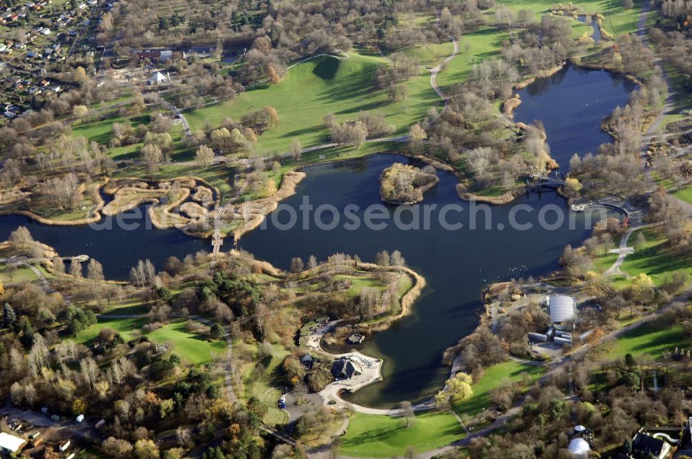 Aerial image Berlin - Herbststimmung im Britzer Garten,benannt nach dem Berliner Ortsteil Britz, wurde für die Bundesgartenschau 1985 angelegt, um der damals vom Umland abgeschnittenen Bevölkerung im Süden West-Berlins einen neuen Landschaftspark zu bieten.Der Britzer Garten wurde auf Ackerflächen und Kleingartenkolonien angelegt; weitestgehend wurden jedoch vorhandene Kleingartenkolonien erhalten. Er befindet sich am südwestlichen Rand des damaligen Berliner Bezirkes Neukölln und grenzt an den Bezirk Tempelhof mit dem Ortsteil Mariendorf an. Er wird durch die Hauptstraßenachsen Mariendorfer Damm, Mohriner Allee, Buckower Damm und Alt-Buckow / Marienfelder Allee eingerahmt. Am Rand dieser Hauptstraßen befindet sich meist offene Wohnbebauung. Noch im Eröffnungsjahr 1985 bestand die planerische Absicht, eine Verlängerung der Berliner Stadtautobahn von der Anschlussstelle Gradestraße durch das Gartengelände hindurch bis zur Berliner Stadtgrenze zu bauen, um dort einen neuen Grenzübergang mit Weiterführung zum Berliner Ring einrichten zu können.Der Britzer Garten hat 90 Hektar Fläche und bietet Natur und Gartenkunst (Rosengarten, Rhododendronhain), Spiellandschaften und ausgedehnte Liegewiesen, Architektur und Kunst (Karl-Foerster-Pavillon), Seen und Hügel sowie bunte Blumenbeete. Neben dem Restaurant am Kalenderplatz steht außerdem die mit 99 Metern Durchmesser größte Sonnenuhr Europas. Sie wurde von den Architekten Jürgen Dirk Zilling, Jasper Halfmann und Klaus Zillich geplant.