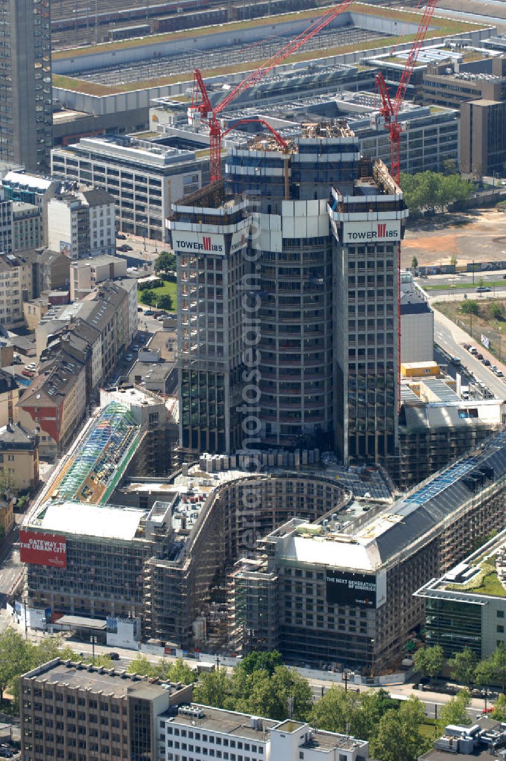 Frankfurt am Main from above - Blick auf die Baustelle des Tower 185 , dem derzeit höchstem, in Deutschland im Bau befindlichen Wolkenkratzer. Bauherr ist die Vivico Real Estate. Die Wirtschaftsprüfungsgesellschaft PricewaterhouseCoopers (PwC) hat bereits vor Baubeginn 60.000 Quadratmeter von insgesamt rund 90.000 Quadratmeter Bürofläche langfristig angemietet und wird hier ihre neue Deutschland-Zentrale beziehen. Den Entwurf für den Tower 185 lieferte der Frankfurter Architekt Christoph Mäckler. Er sieht ein hufeisenförmig angelegtes Sockelgebäude vor, aus dem sich die beiden Hochhaushälften mit einer Aluminium-Glas-Fassade erheben. View of the construction site of Tower 185, currently the highest in Germany under construction skyscraper. Owner is the Vivico real estate.