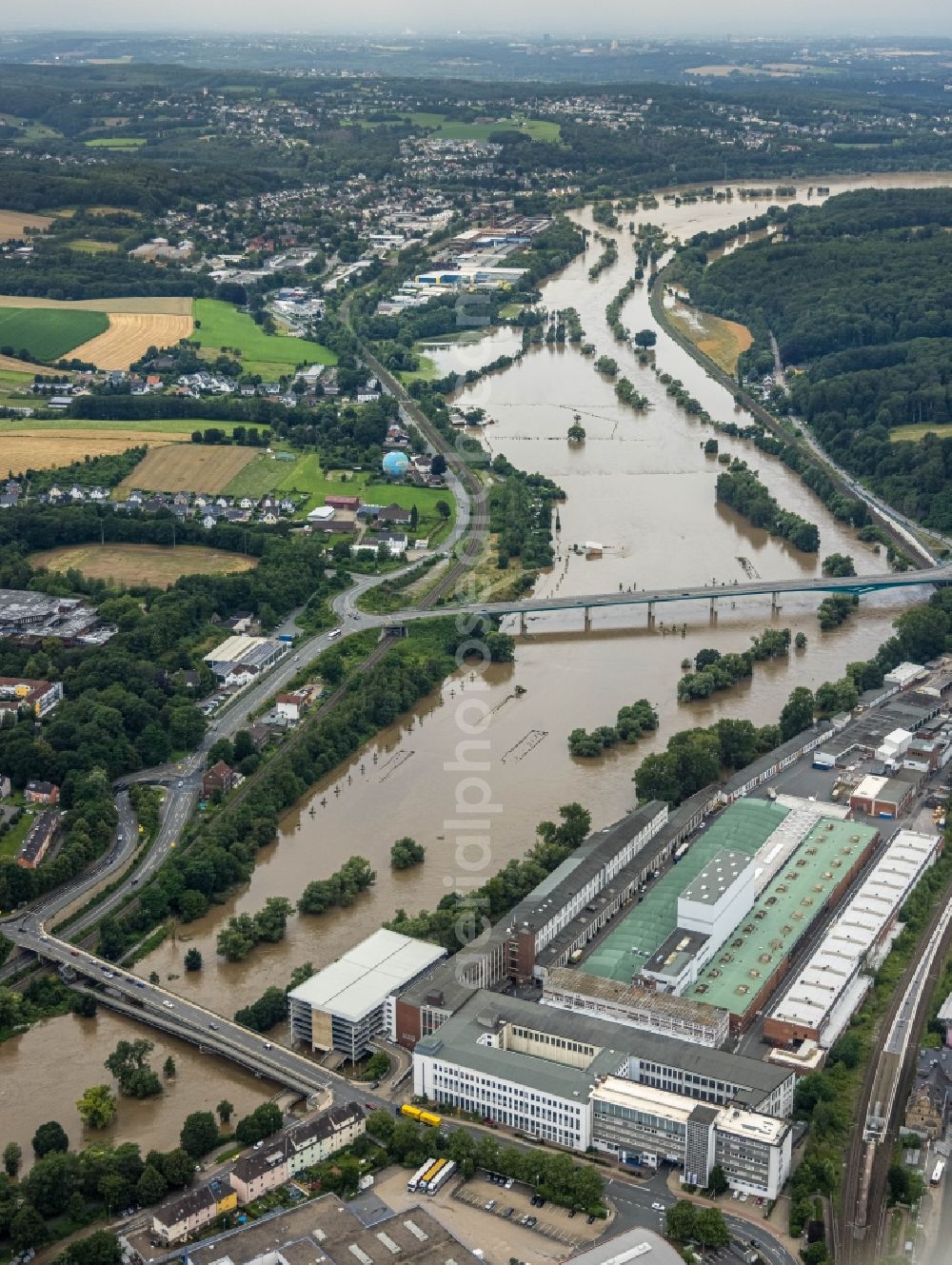 Aerial photograph Wetter (Ruhr) - Flood situation and flooding, all-rousing and infrastructure-destroying masses of brown water on the course of the river Ruhr at the building on the premises of Demag Cranes & Components GmbH on Ruhrstrasse in Wetter (Ruhr) at Ruhrgebiet in the state North Rhine-Westphalia, Germany