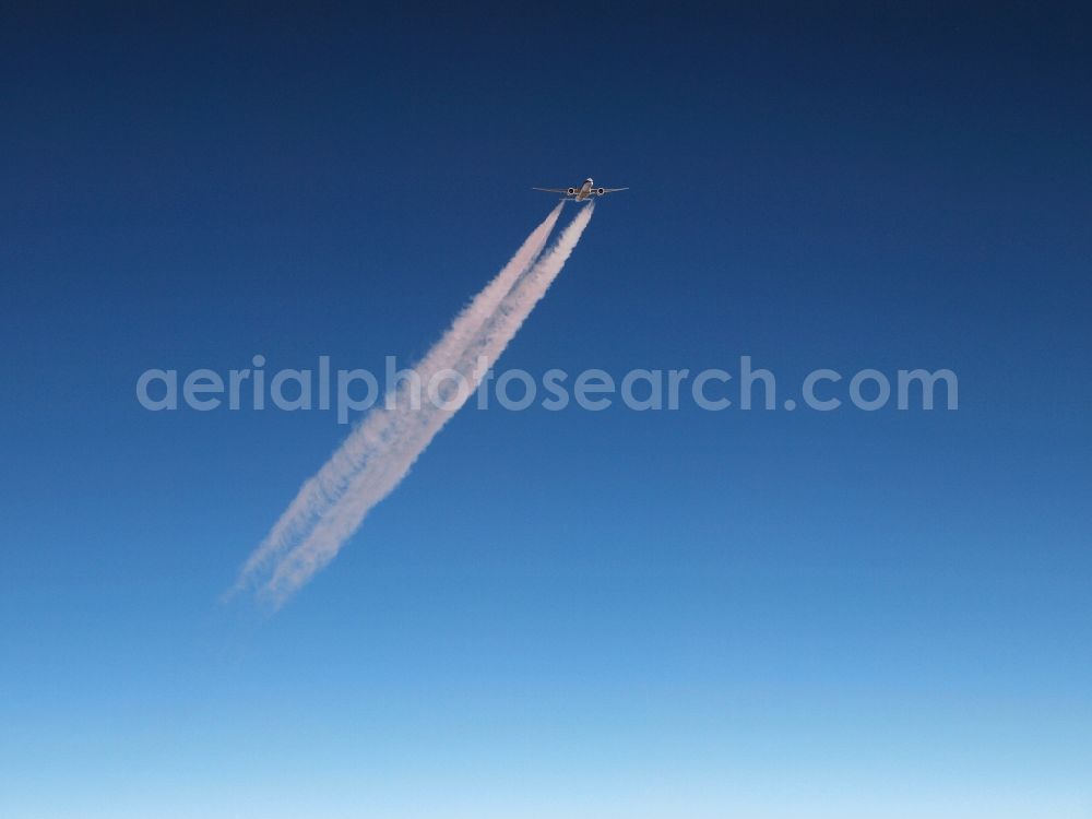 Frankfurt am Main from the bird's eye view: A twin-engine airliner in the upper airspace in Frankfurt am Main in Hessen produces contrail in the blue sky