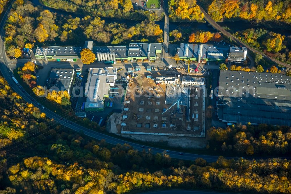 Aerial image Biggen - Industrial and commercial area in Biggen in the state of North Rhine-Westphalia. The area with buildings of HMT Heldener Metalltechnik is located amidst autumnal forest on the riverbank of the river Bigge