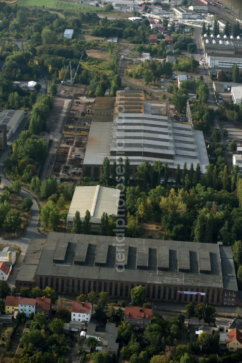 Köthen (Anhalt) from the bird's eye view: Industrial and commercial area along the Hinsdorfer Street in Koethen (Anhalt) in the state Saxony-Anhalt. An empty factory hall is located in the foreground and the premises of the crane manufacturer Kranbau Koethen GmbH is visible in the background