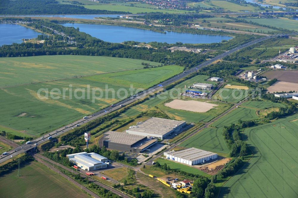 Magdeburg from the bird's eye view: Industrial and commercial area along the A2 in the North of Magdeburg in the state of Saxony-Anhalt. The company buildings and halls along the federal motorway A2 are located on the Western edge of the commercial area North. They are surrounded by fields. The background shows the lakes Barleber See I and II