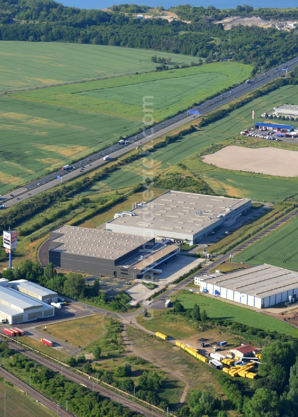 Aerial photograph Magdeburg - Industrial and commercial area along the A2 in the North of Magdeburg in the state of Saxony-Anhalt. The company buildings and halls along the federal motorway A2 are located on the Western edge of the commercial area North. They are surrounded by fields. The background shows the lakes Barleber See I and II