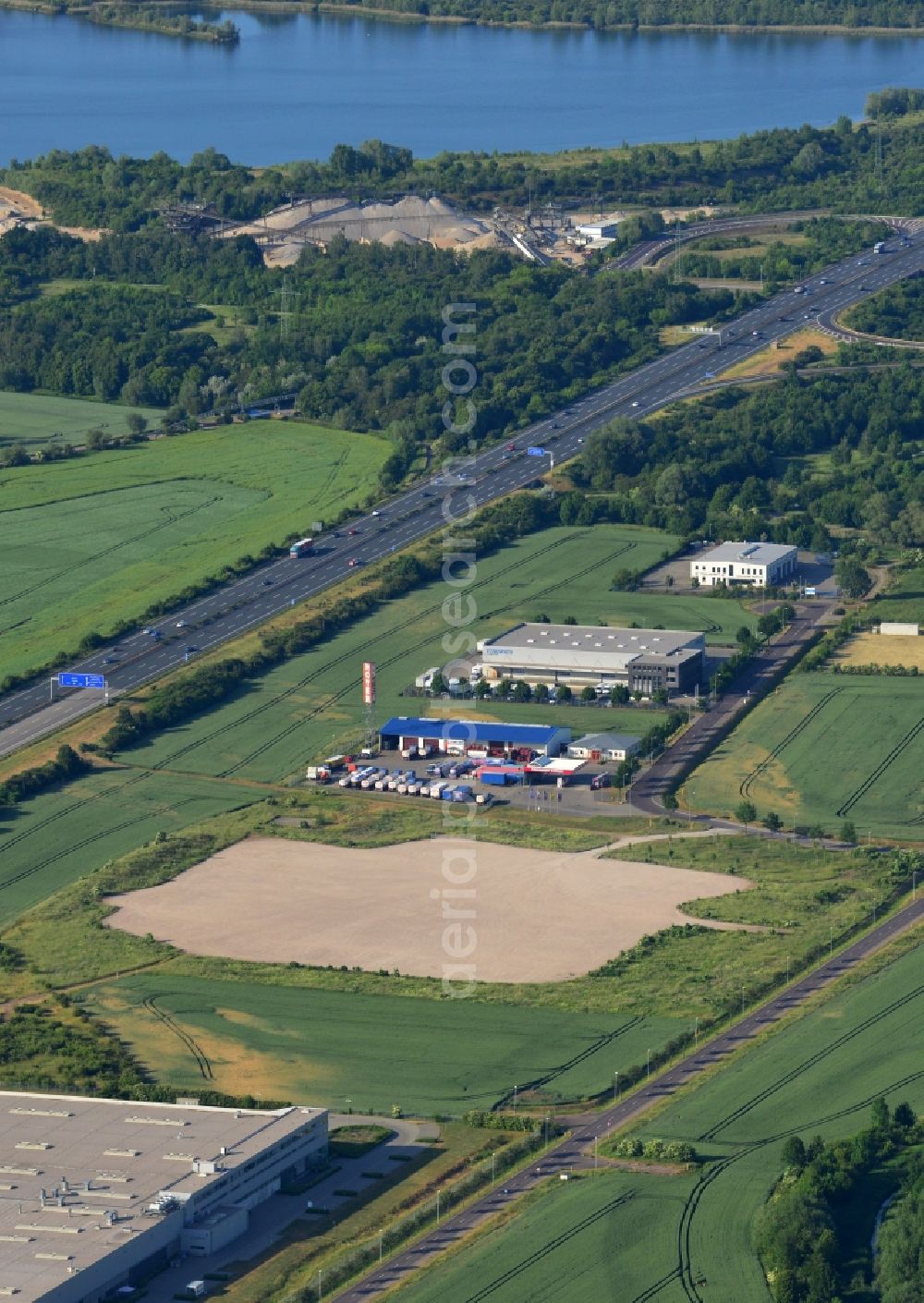 Magdeburg from above - Industrial and commercial area along the A2 in the North of Magdeburg in the state of Saxony-Anhalt. The company buildings and halls along the federal motorway A2 are located on the Western edge of the commercial area North. They are surrounded by fields. The background shows the lake Barleber See II