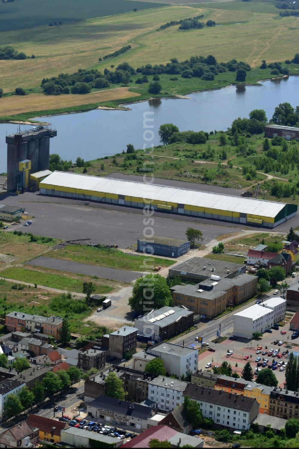 Magdeburg from the bird's eye view: Industrial area on the riverbank of the Elbe and former compound of Fahlberg-List in Magdeburg in the state Saxony-Anhalt.The historic buildings of the former sugar factory with its elongated hall and three silos on the riverbank are listed as protected buildings. The area belongs to the Wusterhuesen and Salbke parts in the South of Magdeburg