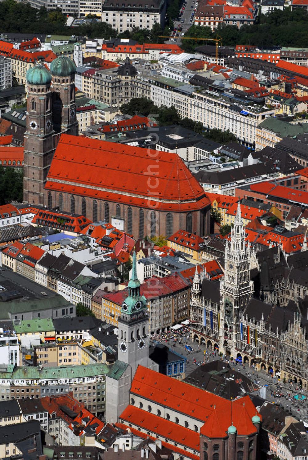 Aerial photograph München - Innenstadt von München mit Blick auf die Frauenkirche, das Neue Rathaus und die Pfarrkirche St. Peter. Die Frauenkirche (Bildmitte) ist die Kathedralkirche des Erzbischofs von München und Freising und gilt als Wahrzeichen der bayerischen Landeshauptstadt. Der dreischiffige spätgotische Backsteinbau mit umlaufendem Kapellenkranz ist 109 m lang, 40 m breit und 37 m hoch. Die Grundsteinlegung für die heutige Frauenkirche erfolgte im Jahr 1468 durch Herzog Sigismund. Da man aus Kostengründen einen gemauerten Backsteinbau errichten wollte, statt auf teure Steinmetzarbeiten zurück zu greifen, wurde die Leitung der Bauarbeiten Jörg von Halspach, einem Maurermeister, übertragen. Im Jahr 1494 wurde die Frauenkirche geweiht. Im Zweiten Weltkrieg schwer beschädigt, wurde die Kirche in der Nachkriegszeit wieder aufgebaut, dabei erhielt sie ihr heutiges eher nüchternes, aber dennoch gewaltiges und markantes Äußeres. Von der ursprünglichen Ausstattung sind noch einige mittelalterliche Skulpturen und die mittelalterlichen Glasgemälde der Chorfenster erhalten geblieben. Mit ihrer herrlichen zentralen Lage inmitten einer großzügigen Fußgängerzone, die zwischen Karlsplatz und Marienplatz eingerichtet wurde, ist die Frauenkirche eine der meistbesuchtesten Sehenswürdigkeiten Münchens. Kontakt: Dom Zu Unserer Lieben Frau, Frauenplatz 12, 80331 München, Tel.: 089/290082-0, E-Mail: dompfarramt@muenchner-dom.de,