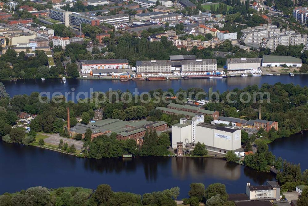 Berlin-Spandau from the bird's eye view: Blick auf die Insel Eiswerder. Die 140.000 m² große Insel liegt inmitten der hier zum Spandauer See erweiterten Havel. Etwa die Hälfte der Insel ist bewaldet. Die im südlichen Teil der Insel befindlichen Gebäude folgen nicht der Bauflucht der Spandauer Uferbebauung, sondern um 45° hierzu gedreht der Achse der Zitadelle.Nach dem Zweiten Weltkrieg dienten die verbliebenen Hallen und Flächen auf dem Eiswerder als Lagerungs- und Umschlagplatz für Getreide, auf dem Salzhof hingegen wurden Tanklager errichtet. Von 1953 bis 1990 lagerte hier der Berliner Senat die erweiterten Senatsreserven. Die Rhenus AG & Co. KG errichtete auf der Insel einen Lokschuppen und eine Wartungsgrube und übernahm 1988 von hier aus die Betriebsführung der Siemens-Güterbahn. Der Eiswerder wurde auch zum Standort verschiedener Bootsclubs