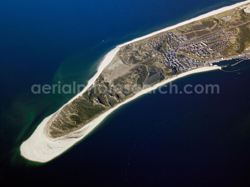 Hörnum ( Sylt ) from the bird's eye view: Blick auf die Insel Sylt. Sylt (dänisch Sild, friesisch Söl) ist die größte nordfriesische Insel. Sie erstreckt sich in Nord-Süd-Richtung vor der Nordseeküste Schleswig-Holsteins. Bekannt ist die nördlichste deutsche Insel vor allem für ihre touristisch bedeutenden Kurorte Westerland, Kampen und Wenningstedt sowie für den knapp 40 Kilometer langen Weststrand. Wegen ihrer exponierten Lage in der Nordsee kommt es zu kontinuierlichen Landverlusten bei Sturmfluten. Seit 1927 ist Sylt über den Hindenburgdamm mit dem Festland verbunden. Island of Sylt. Sylt is the largest North Frisian island of Schleswig-Holstein